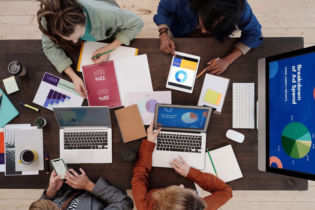 Une équipe variée travaille ensemble sur des stratégies de marketing numérique autour d’une table, avec des ordinateurs portables et des tablettes.